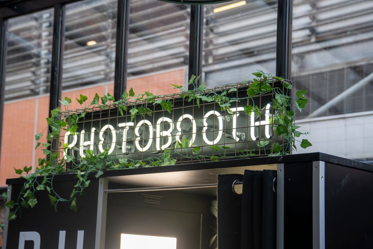 Neon 'Photobooth' sign at the entrance of an event stand