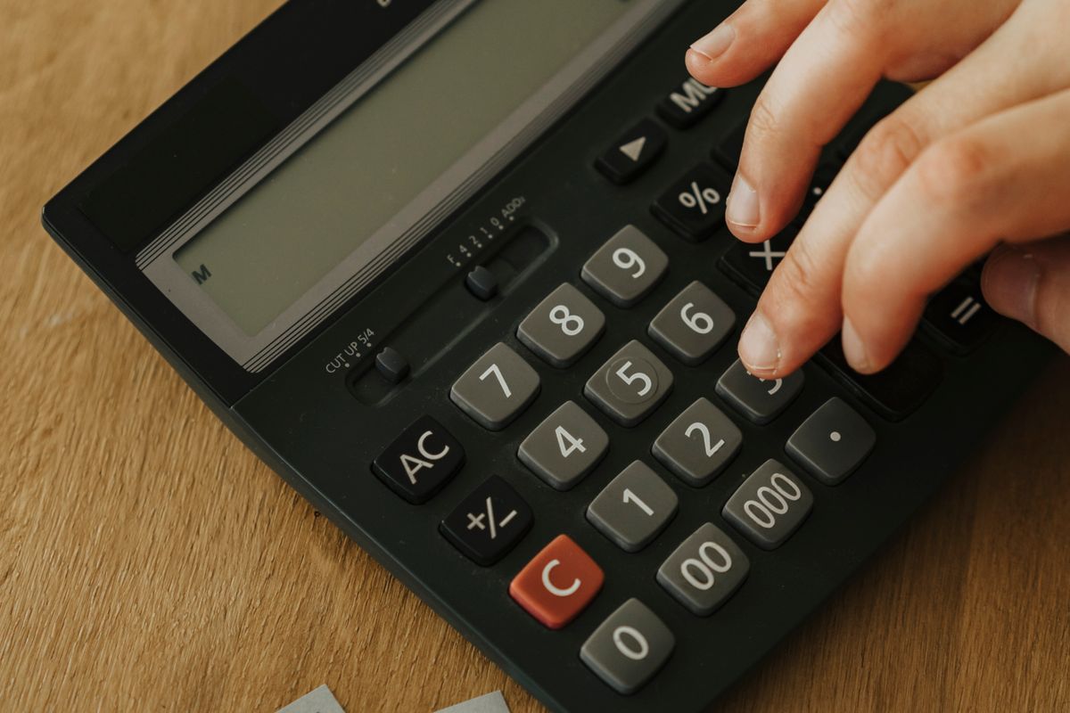 Hand using a calculator next to banknotes